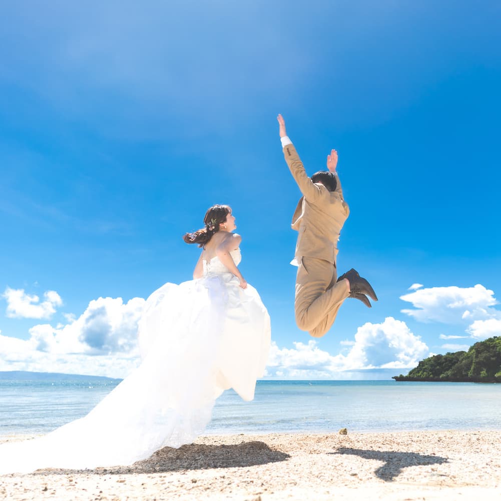 石垣島のビーチで海に向かってジャンプする新郎新婦