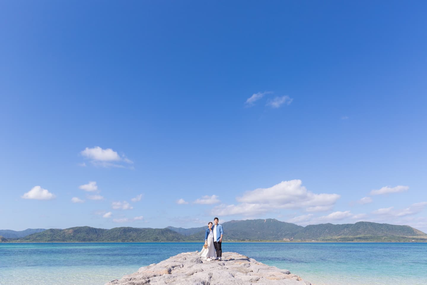 小浜島の海を背景に立つ新郎新婦
