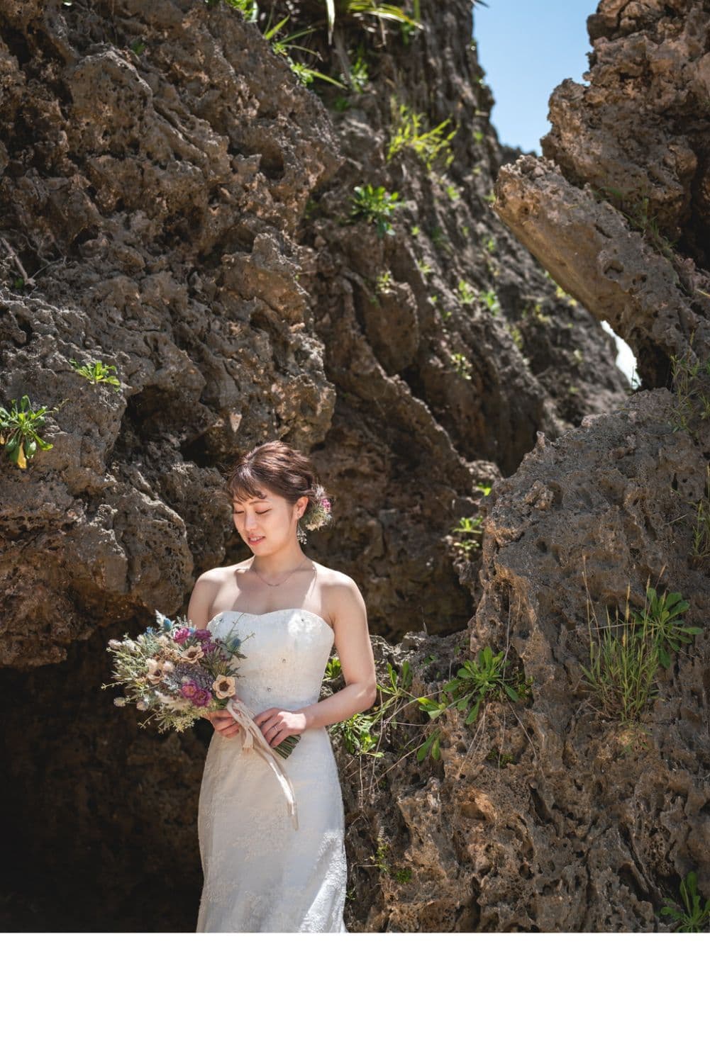 石垣島の海にある岩場でブーケを眺める新婦