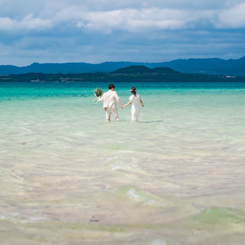 幻の島で海に入って歩く新郎新婦