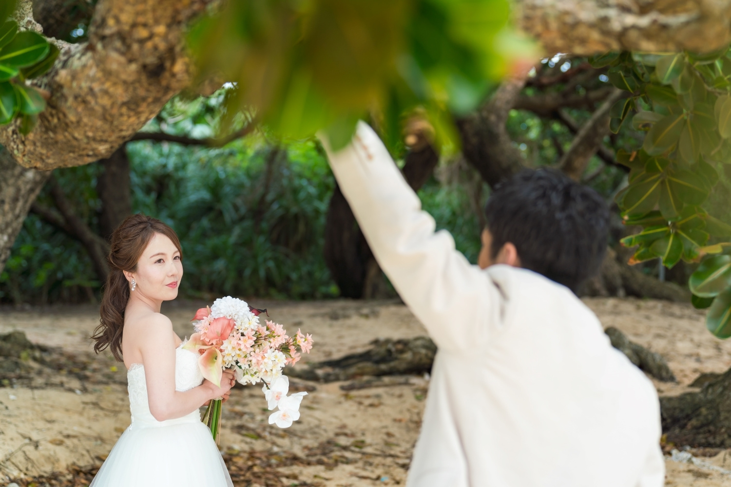 ビーチの緑に囲まれて見つめ合う新郎新婦