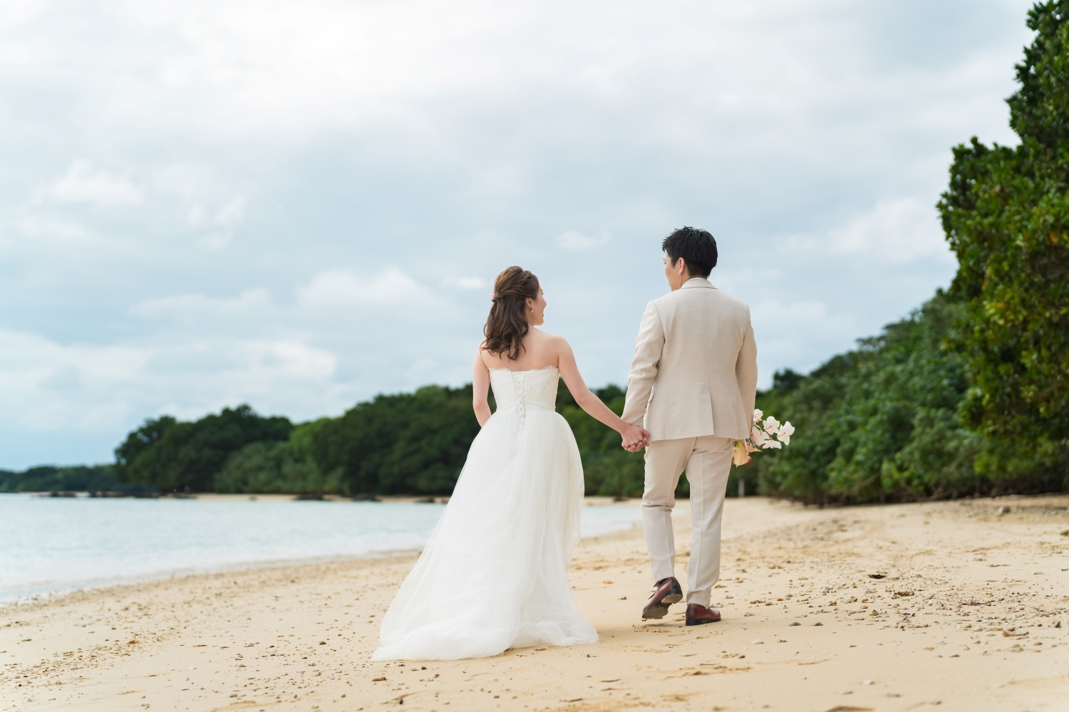 浜辺を歩く新郎新婦の後ろ姿