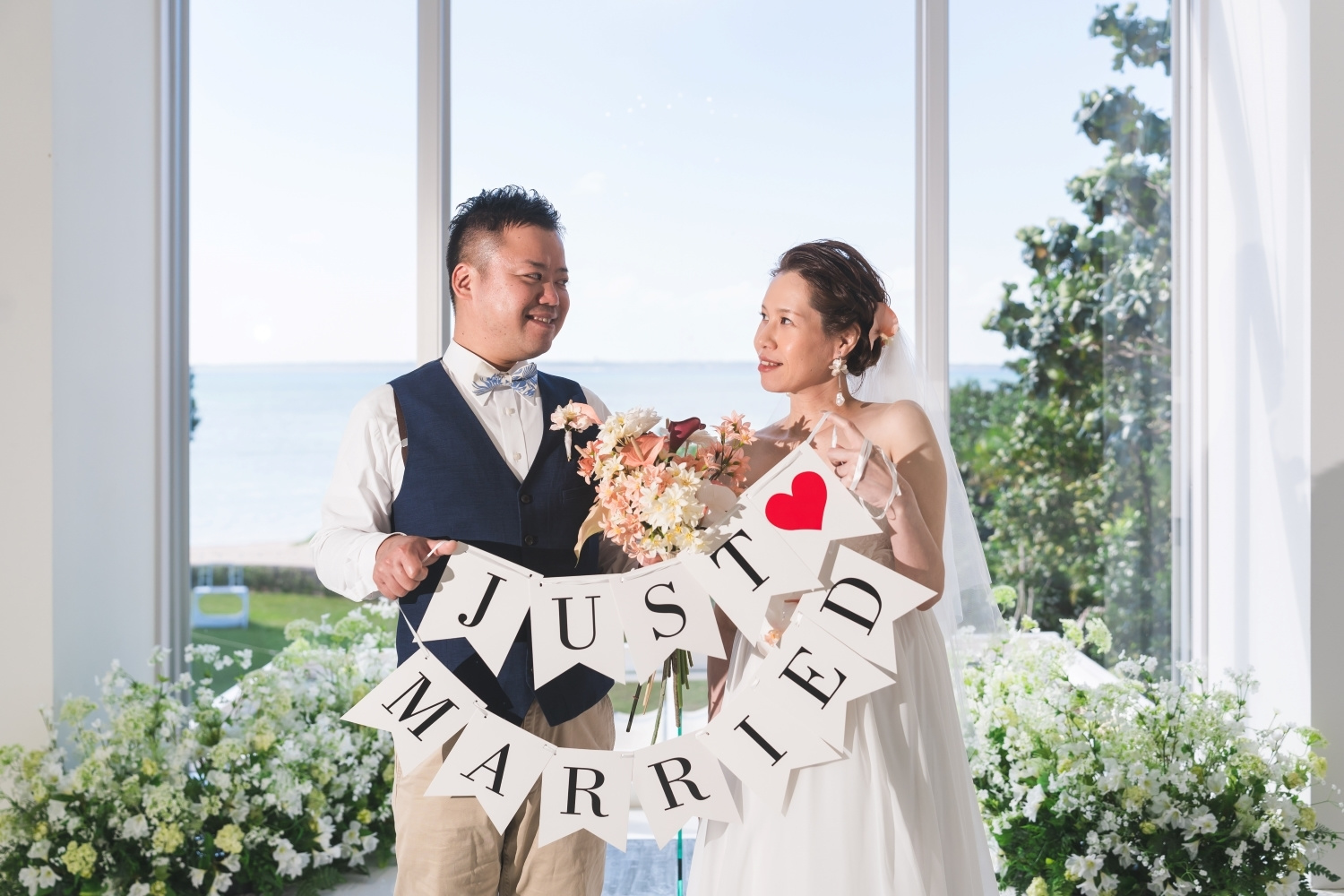 チャペルの祭壇に立ちガーランドを持つ新郎新婦