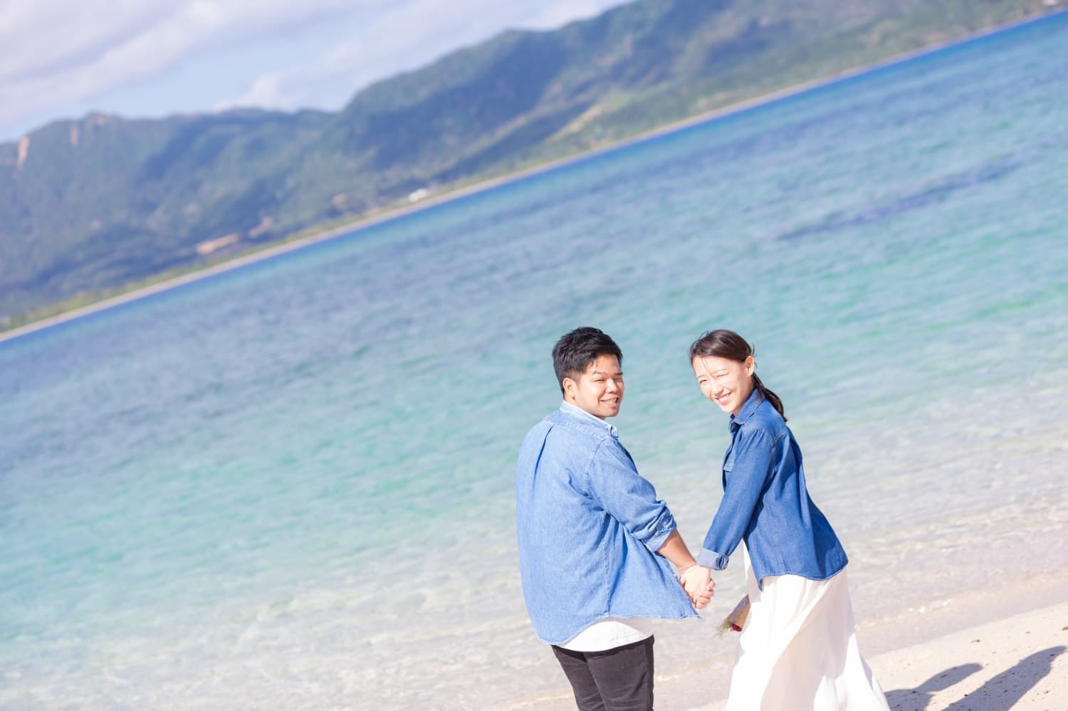 小浜島の海で手を繋いで振り返る新郎新婦