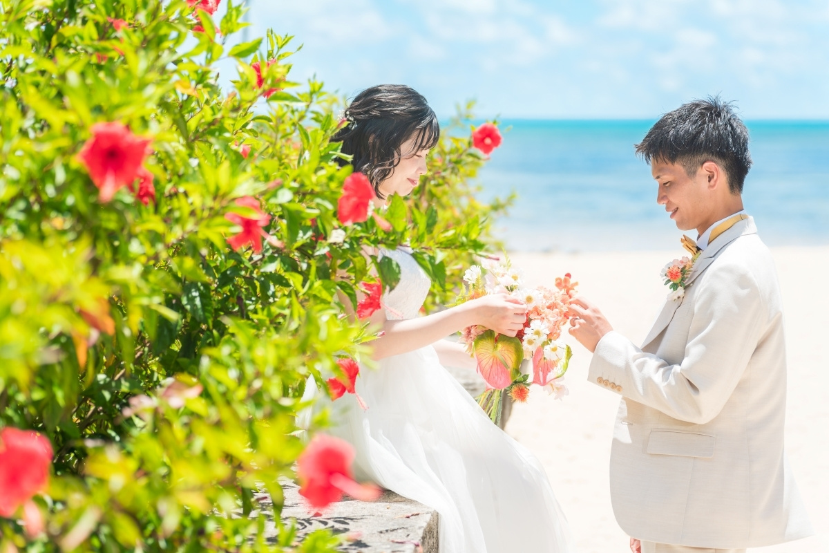 石垣島の海を背景にハイビスカスに囲まれる新郎新婦