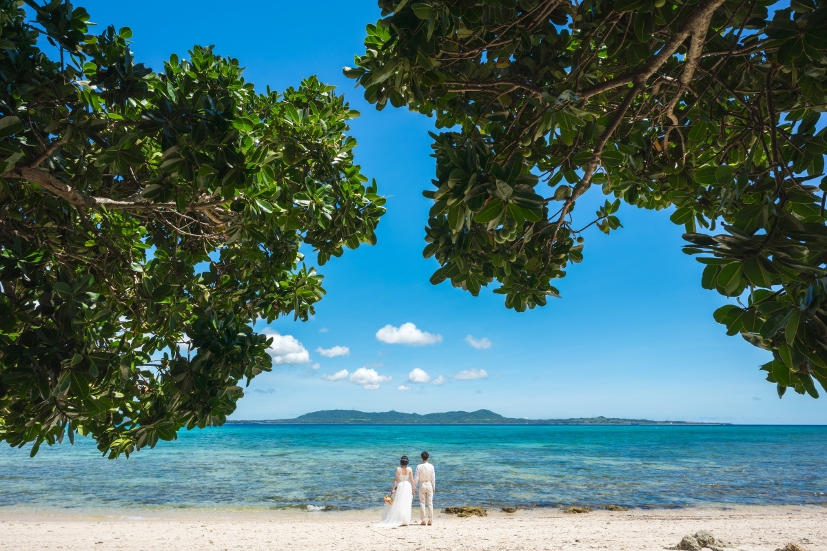 石垣島の海を背景に向かい合って顔を寄せ合う新郎新婦