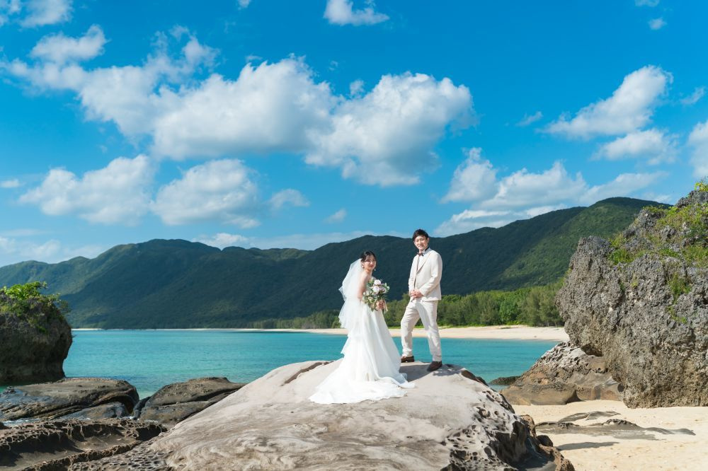 青空を背景にブーケを掲げている新婦