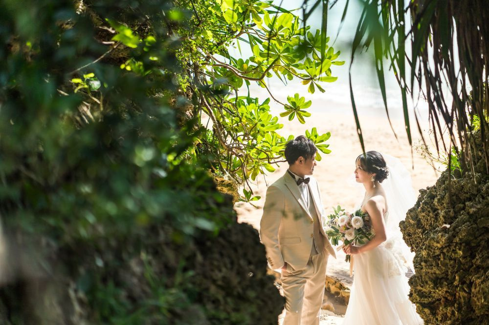 石垣島の海を背景に向かい合って顔を寄せ合う新郎新婦