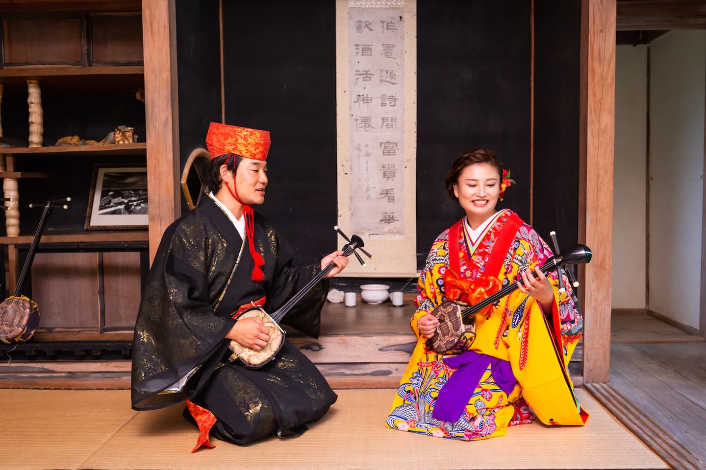 やいま村にある古民家の中で三線を弾く新郎新婦