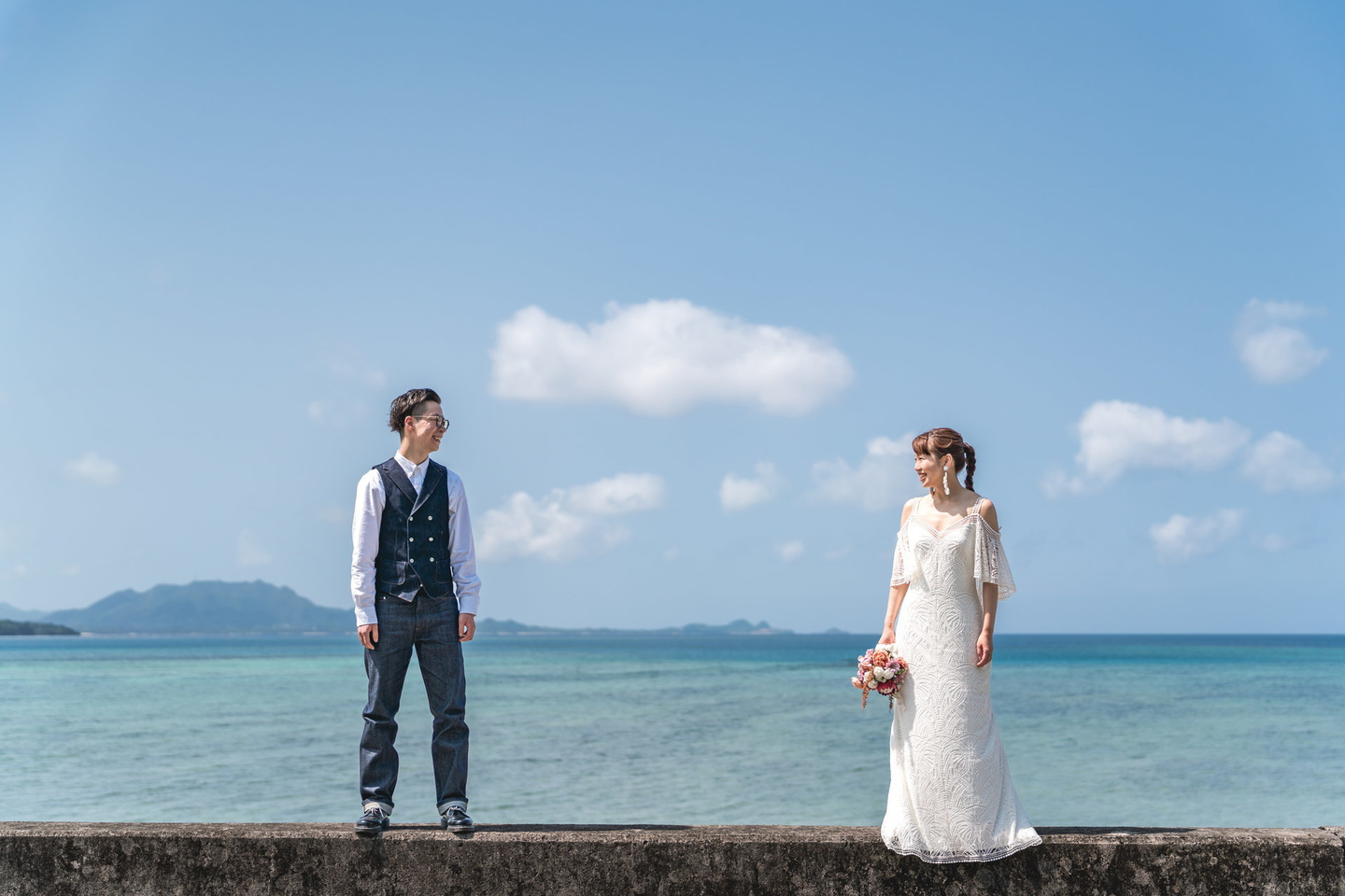 青空を背景にブーケを掲げている新婦