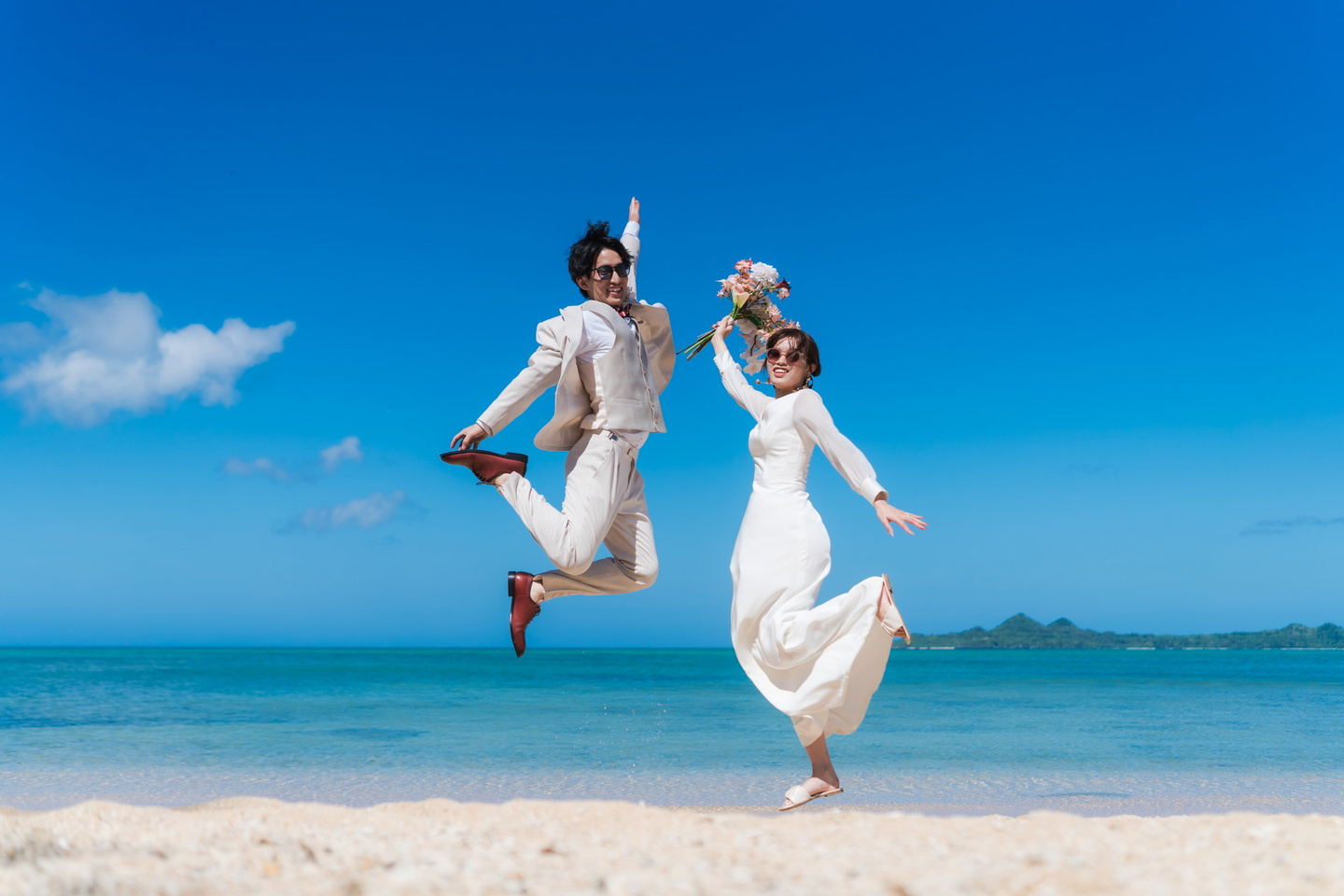 石垣島の海を背景に向かい合って顔を寄せ合う新郎新婦