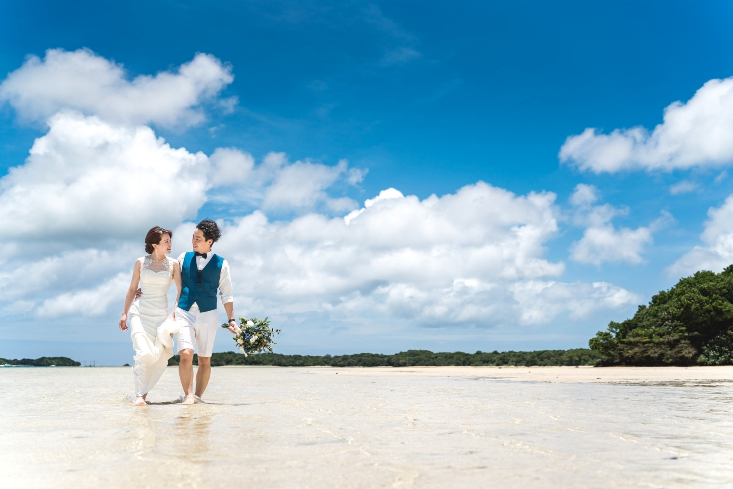 遠浅の海を歩く新郎新婦