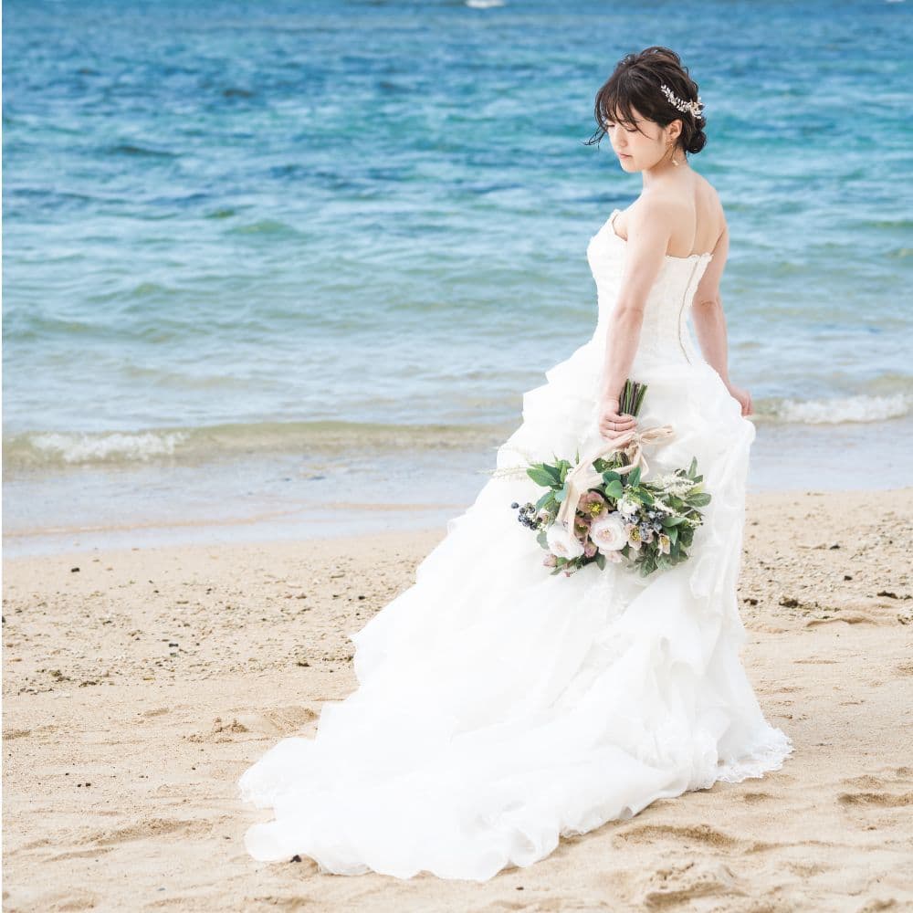ビーチで海を背景にブーケを下ろして立つ新婦