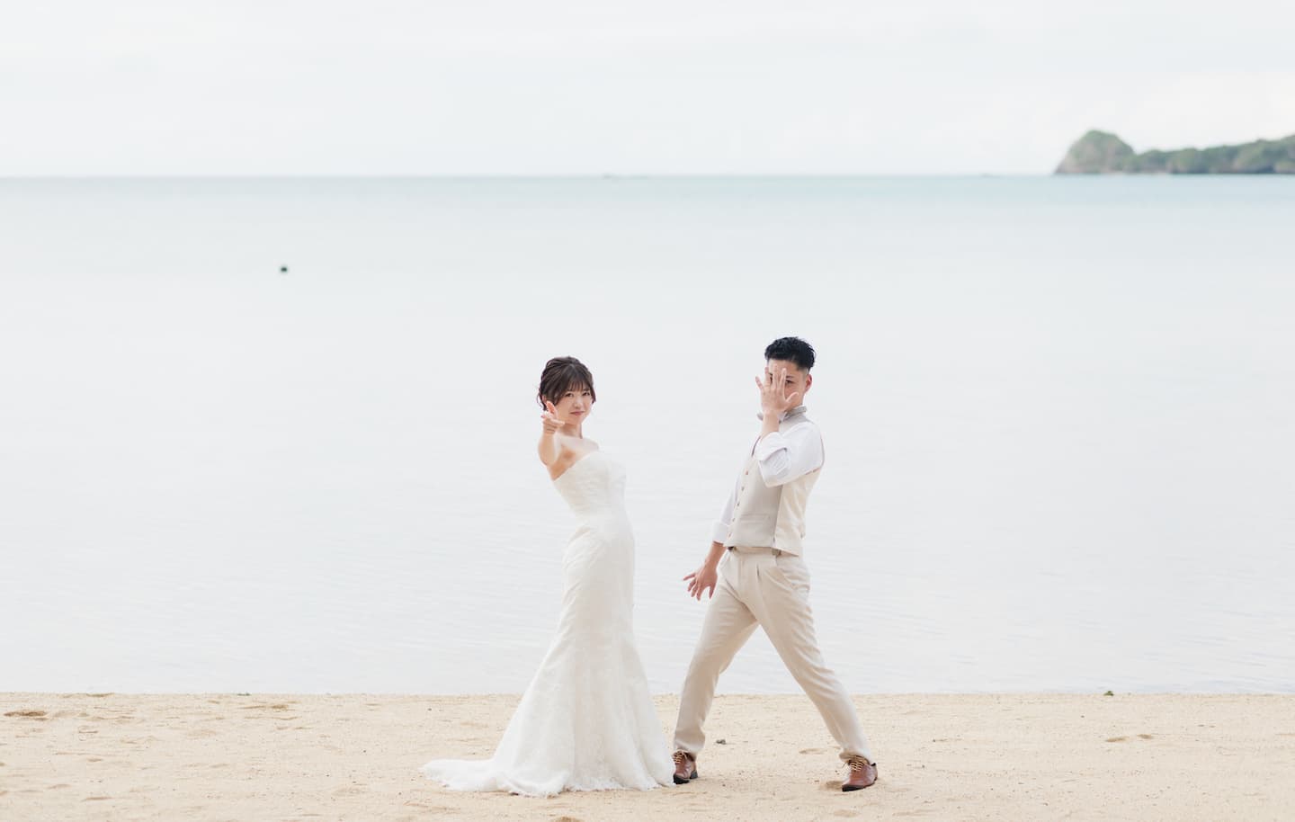 底地ビーチで海を背景にポーズを決める新郎新婦