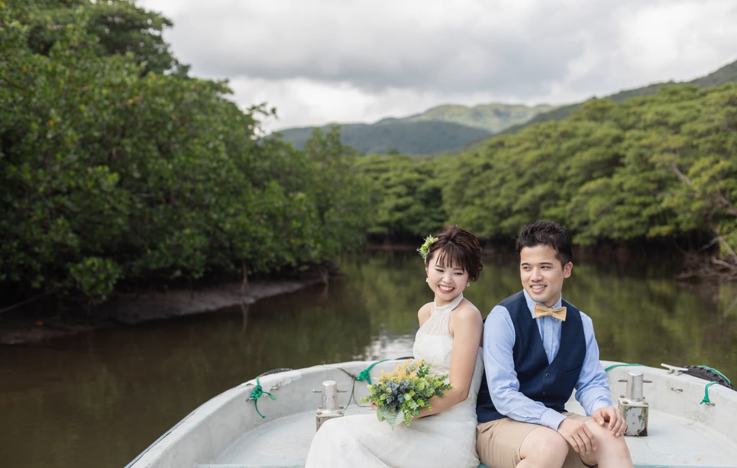 西表島の仲間川でボートに座る新郎新婦