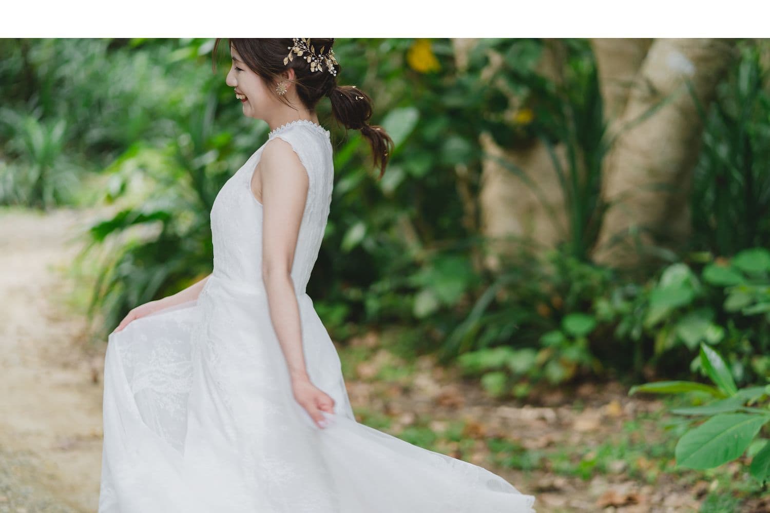 木々を背景にドレスを靡かせて笑う新婦