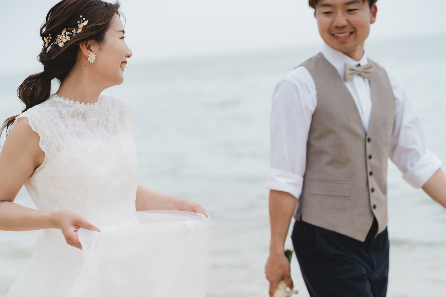 海を背景に見つめ合って歩く新郎新婦
