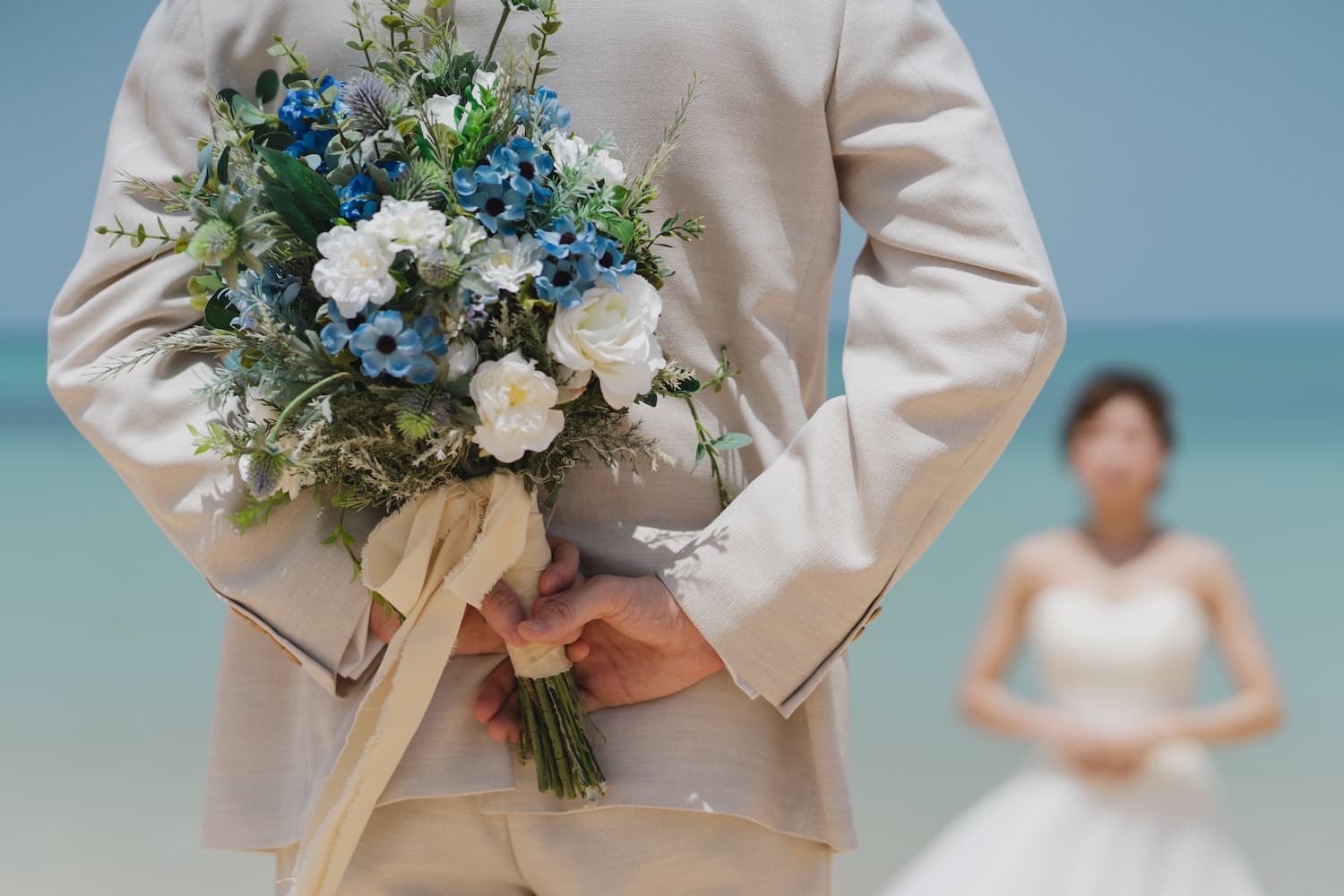 石垣島のビーチで新婦へのブーケを後ろでに持つ新郎の後ろ姿