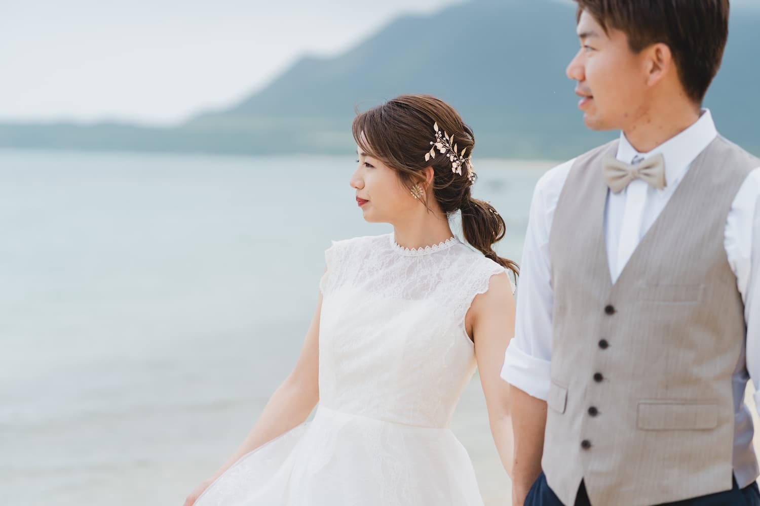 海を眺めながら浜辺を歩く新郎新婦