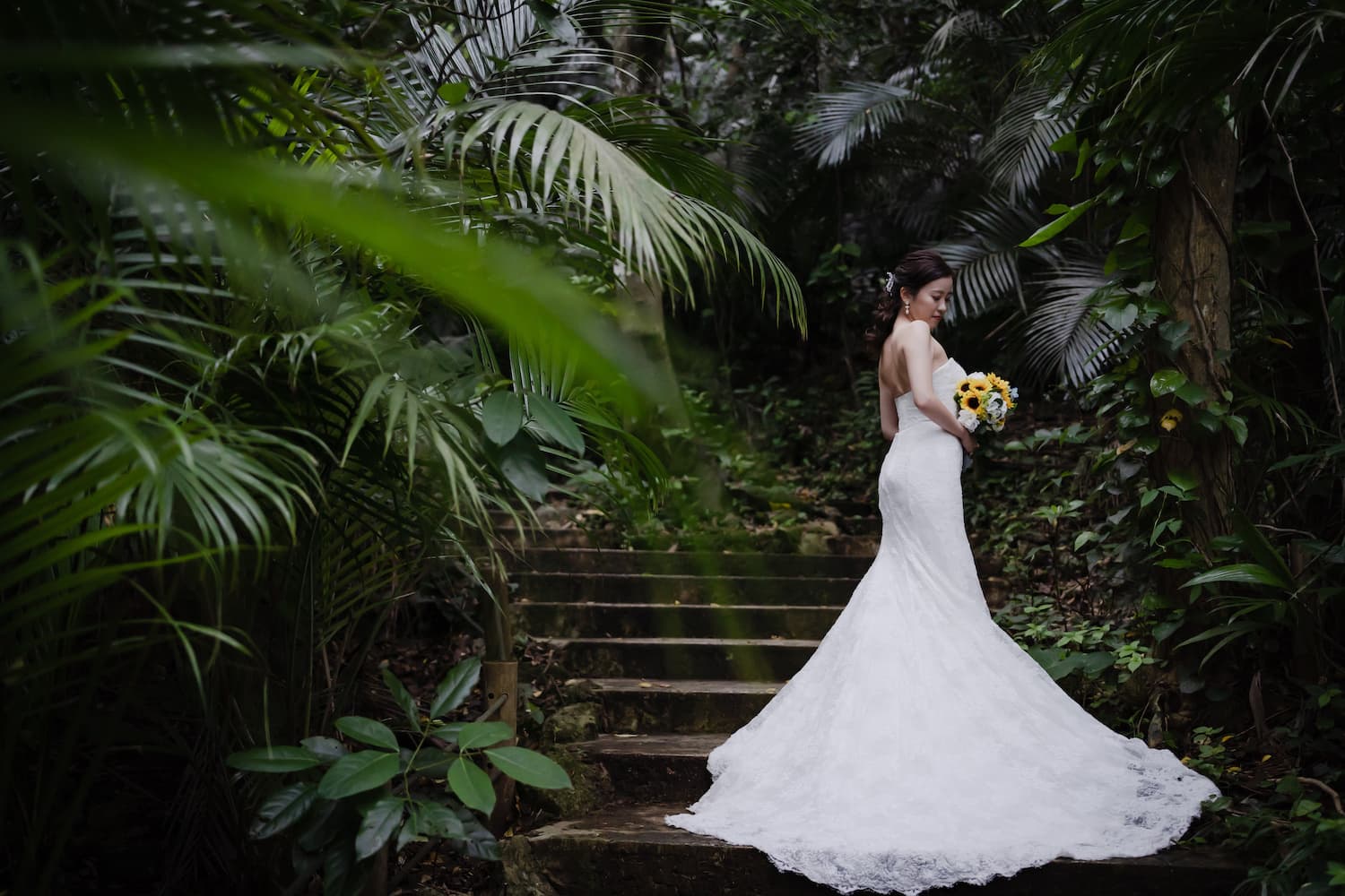 緑に囲まれた石階段を登る新婦