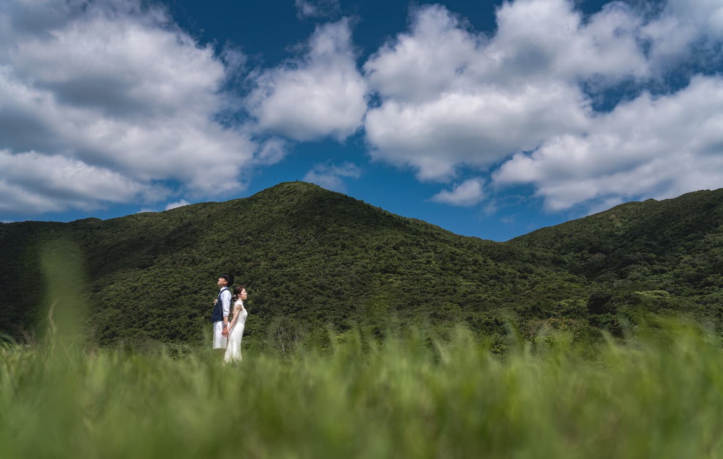 西表島の山を背景に立つ新郎新婦