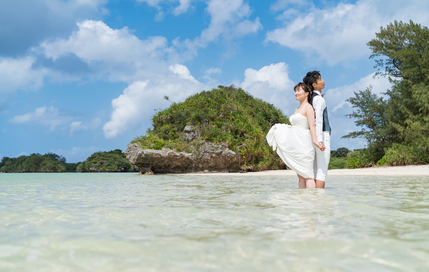 川平湾で海に入って背中合わせに立つ新郎新婦