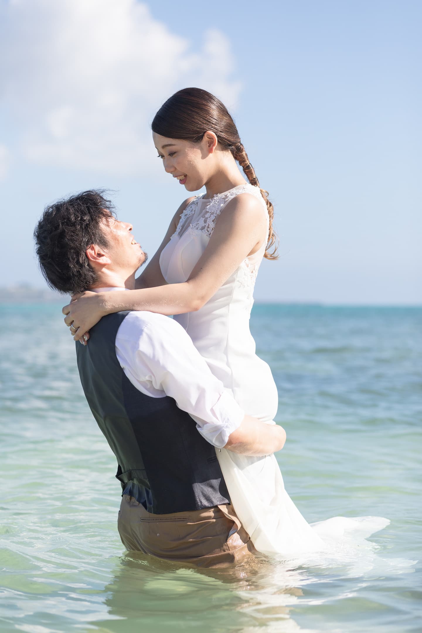 海に入って新婦を抱き上げる新郎