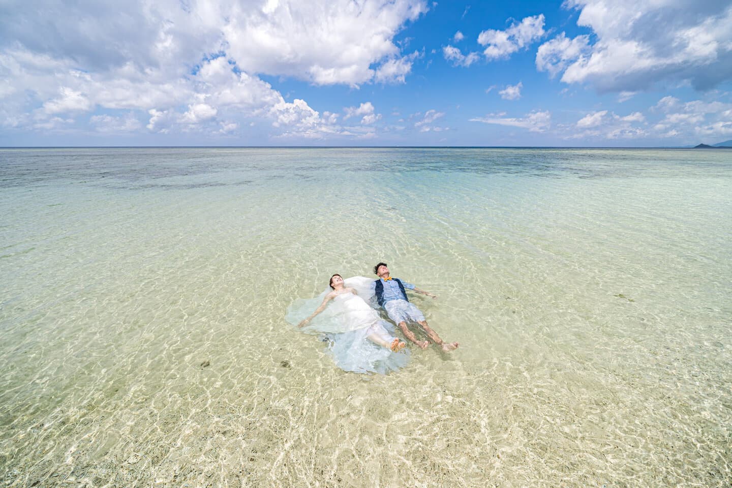 海に入って浮かんでいる新郎新婦のドローン写真