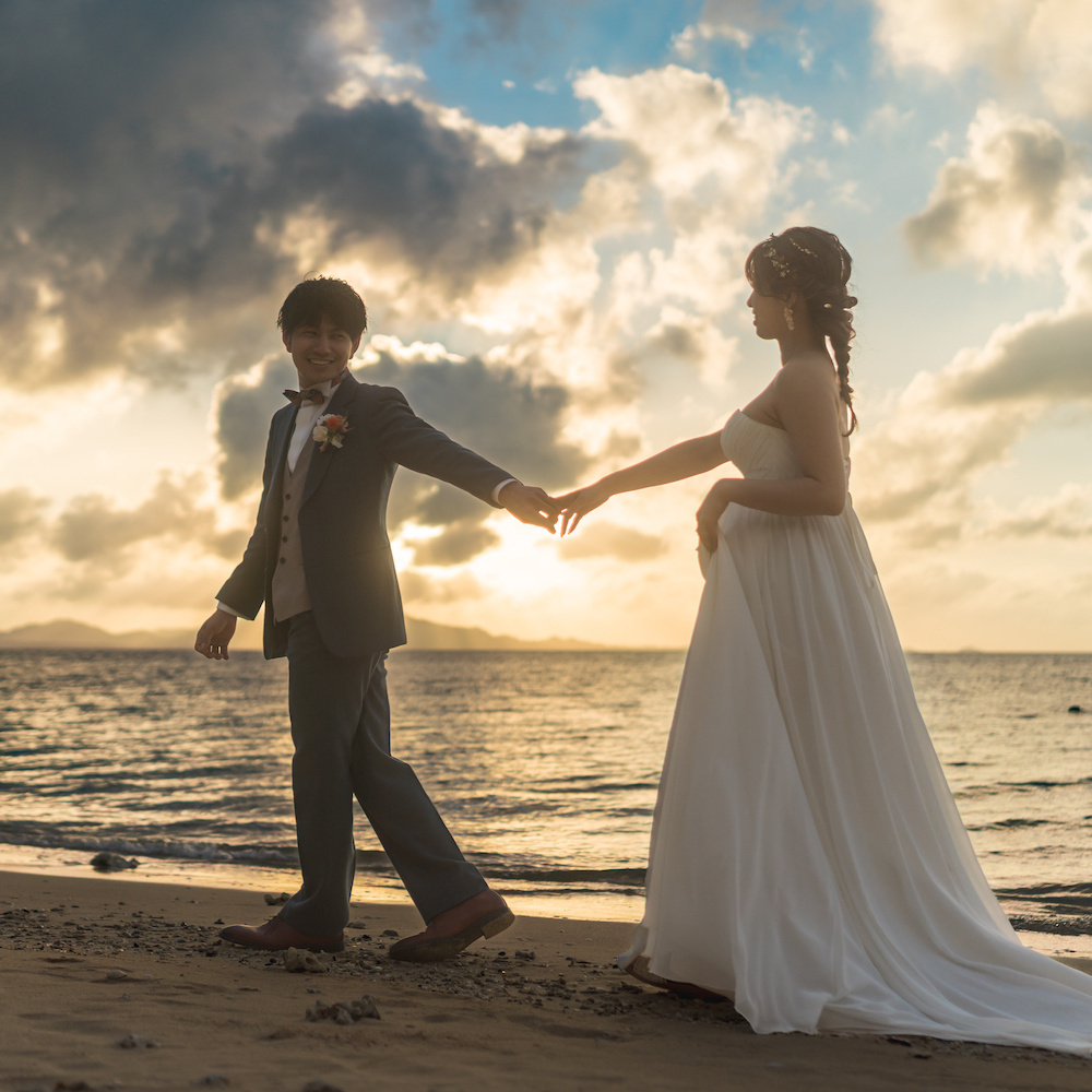 海を見渡す崖で肩を抱き合う新郎新婦の後ろ姿