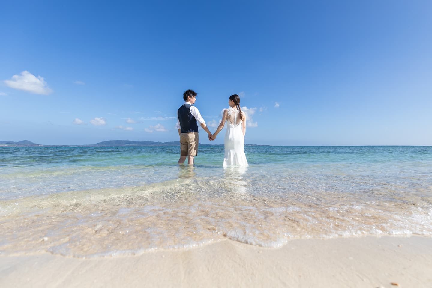 手を取り合って海に入っていく新郎新婦