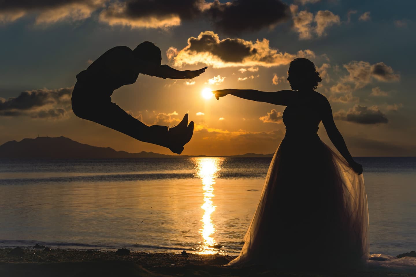 夕日を背景にポーズを決める新郎新婦のシルエット
