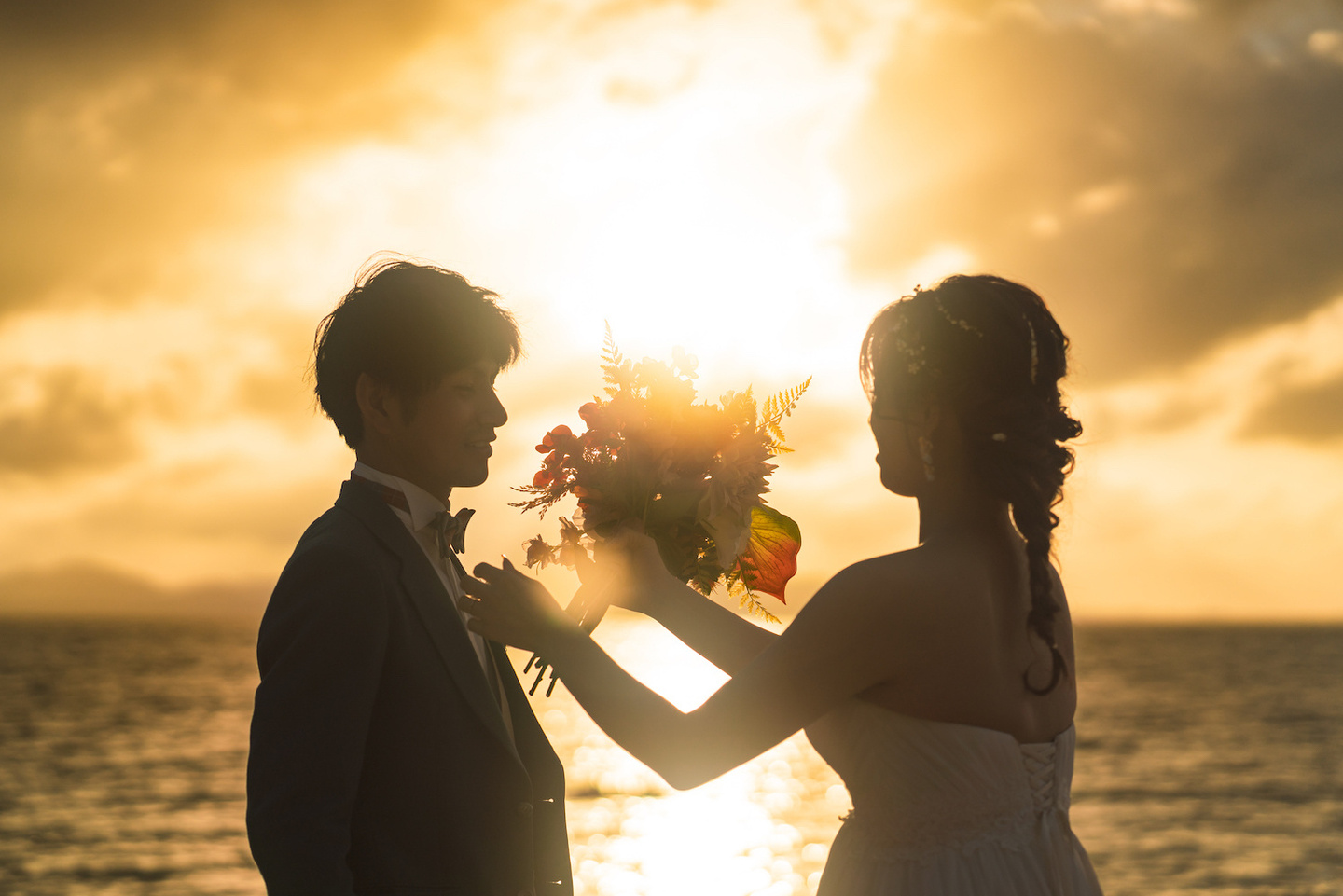 夕日が沈む海を背景に向かい合う新郎新婦