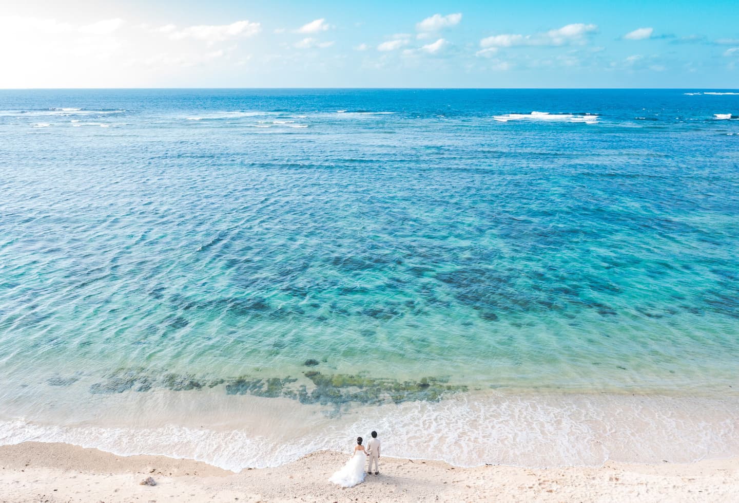 浜辺に立つ新郎新婦を写したドローン写真