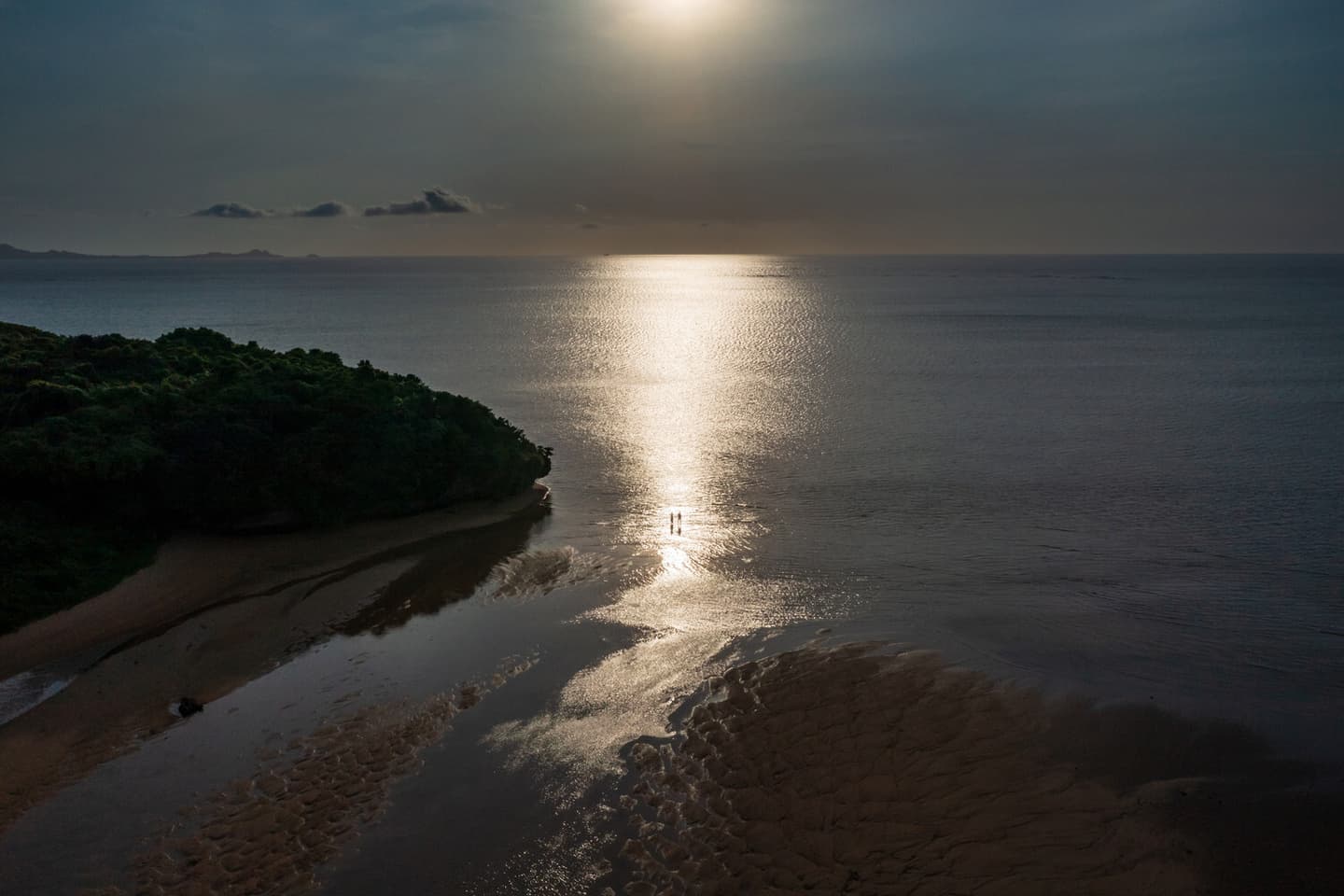 夕日が沈む海に立つ新郎新婦を写したドローン写真