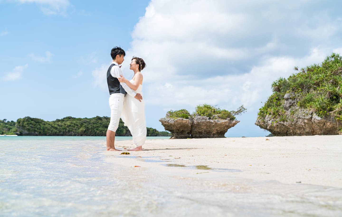 川平湾の無人島で海に足を入れて抱き合う新郎新婦