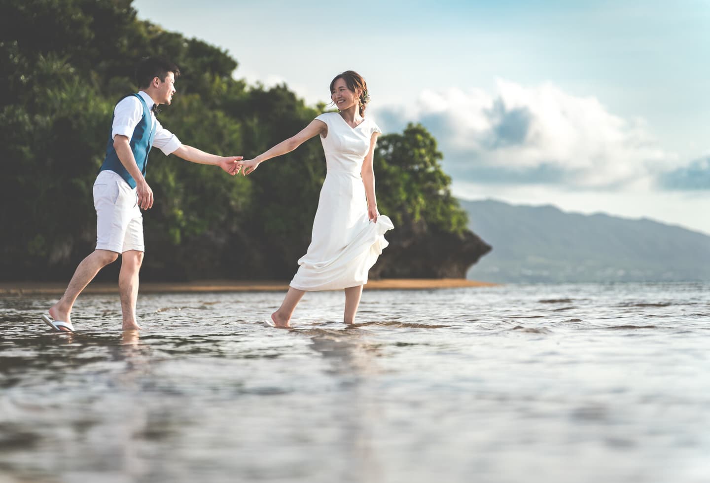 海に向かって新郎の手を引く新婦