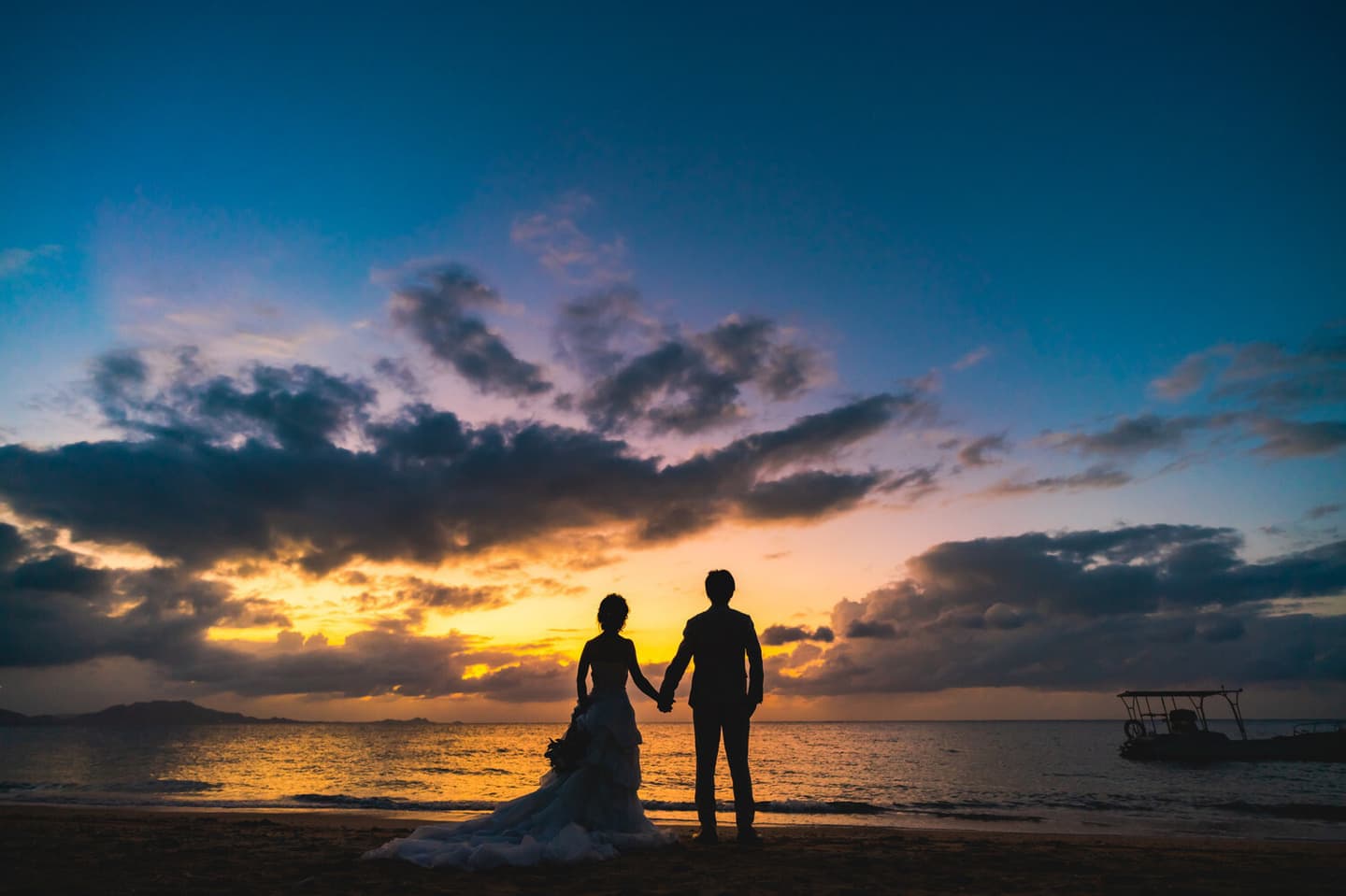 海で夕焼けを眺める新郎新婦の後ろ姿