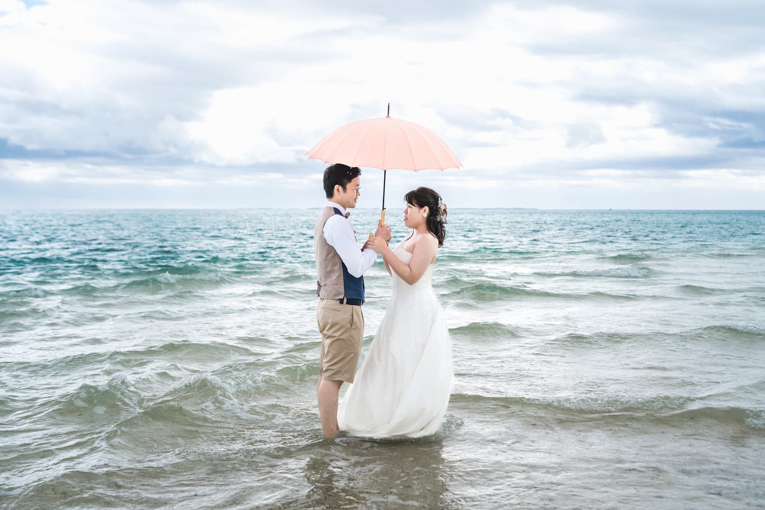 海の中に入って二人で傘をさす新郎新婦