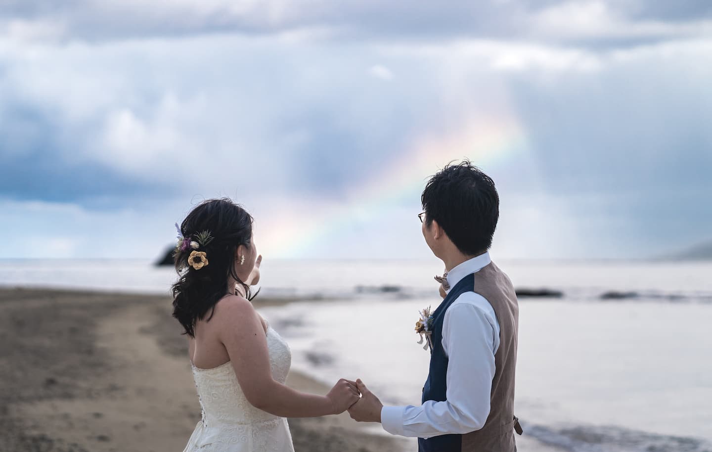 手を取り合って虹を眺める新郎新婦