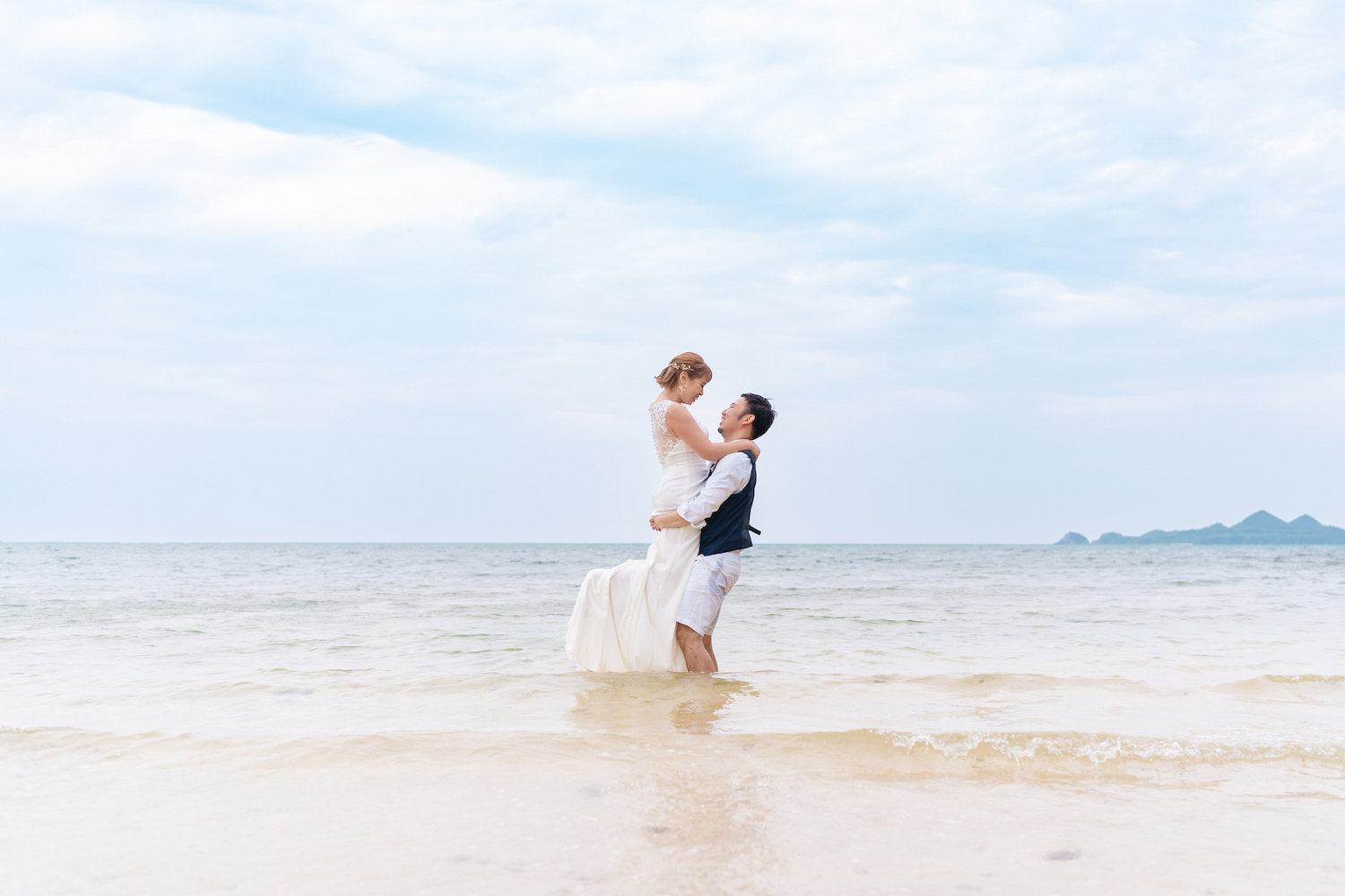 海に入って新婦を抱き上げる新郎
