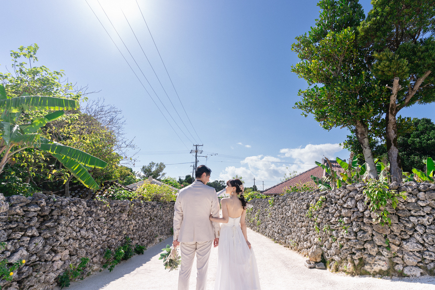 竹富島の集落で腕を組んで見つめ合う新郎新婦