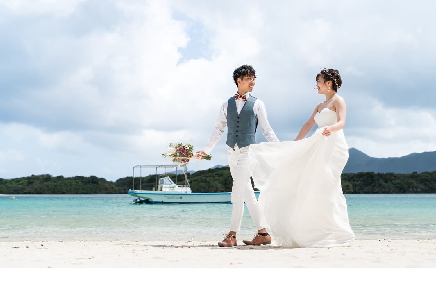 川平湾を背景に歩く新郎新婦