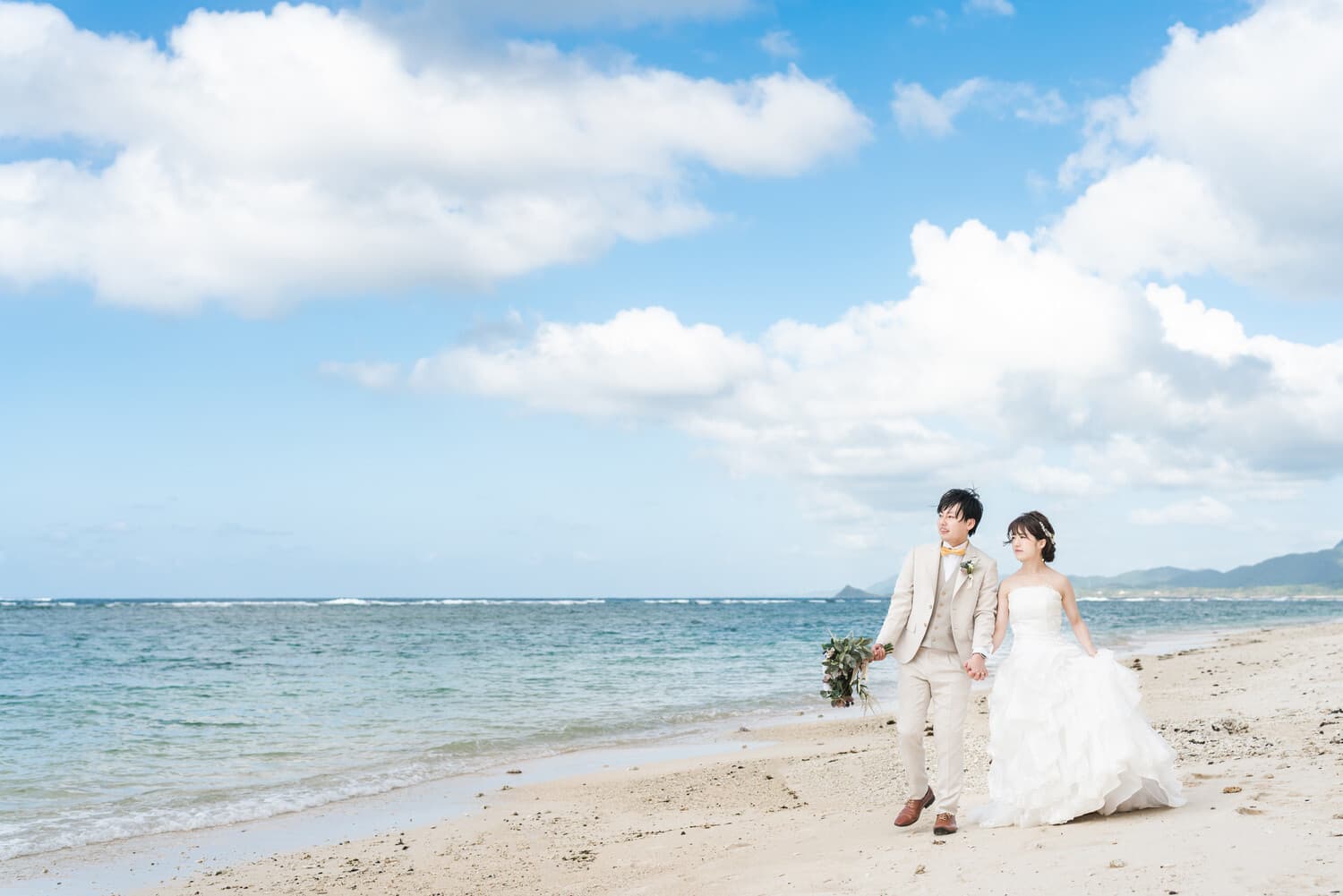 米原ビーチの浜辺を歩く新郎新婦