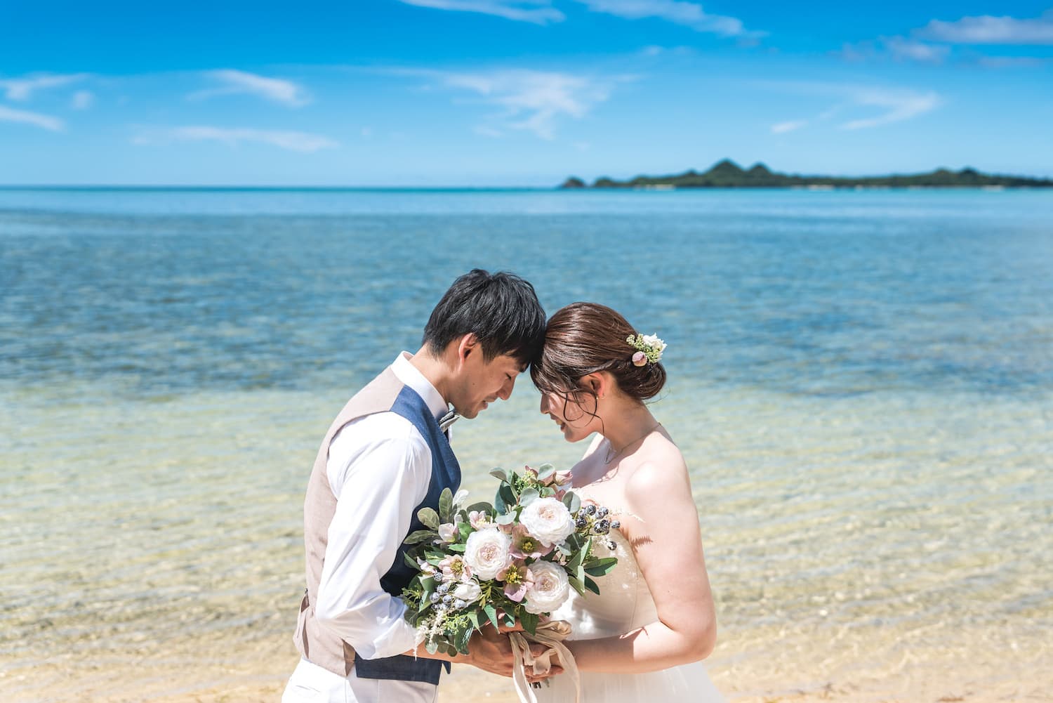 海を背景におでこをくっつける新郎新婦