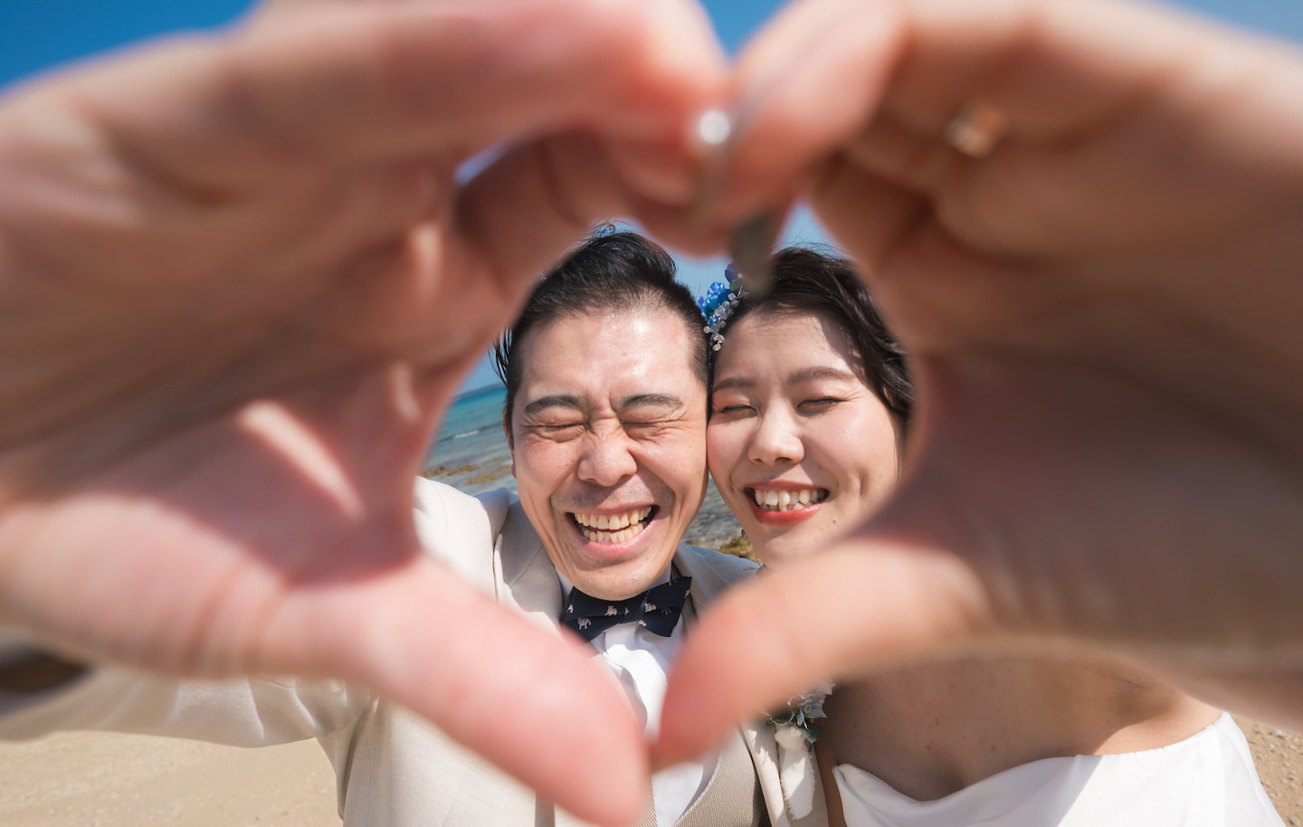 手で作ったハートの中で笑顔を見せる新郎新婦