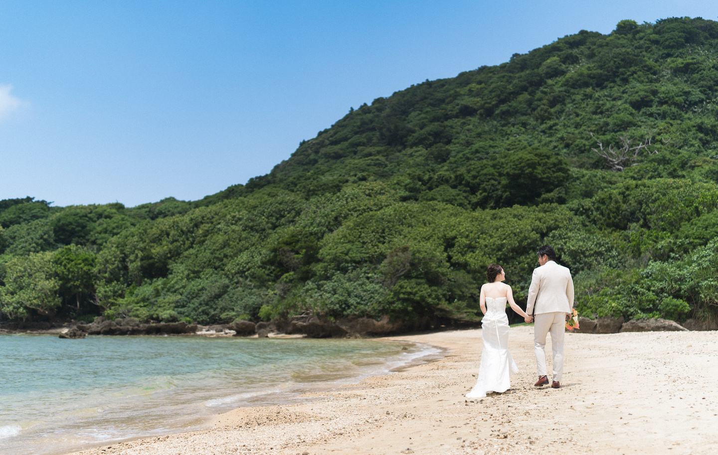 海の見える道で顔を寄せ合う新郎新婦
