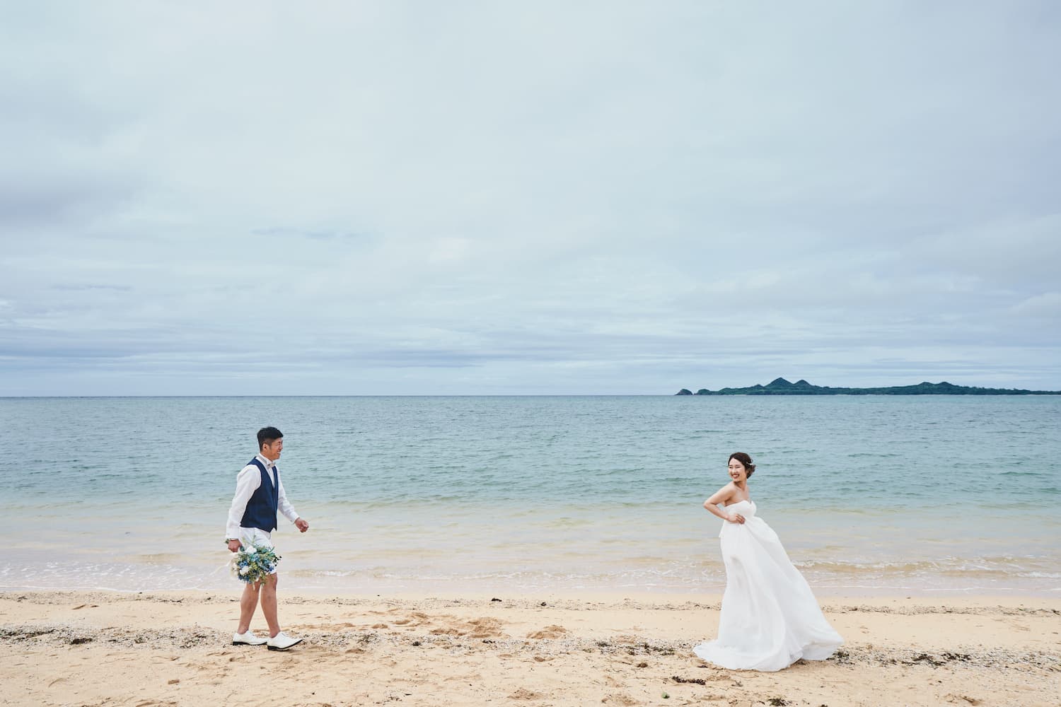 浜辺を歩く新郎新婦