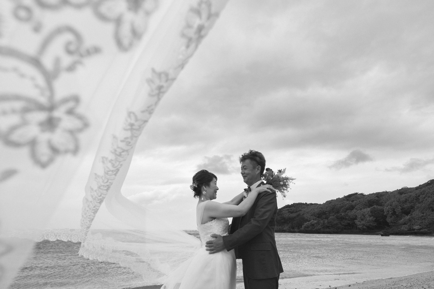ベールをなびかせて抱き合う新郎新婦