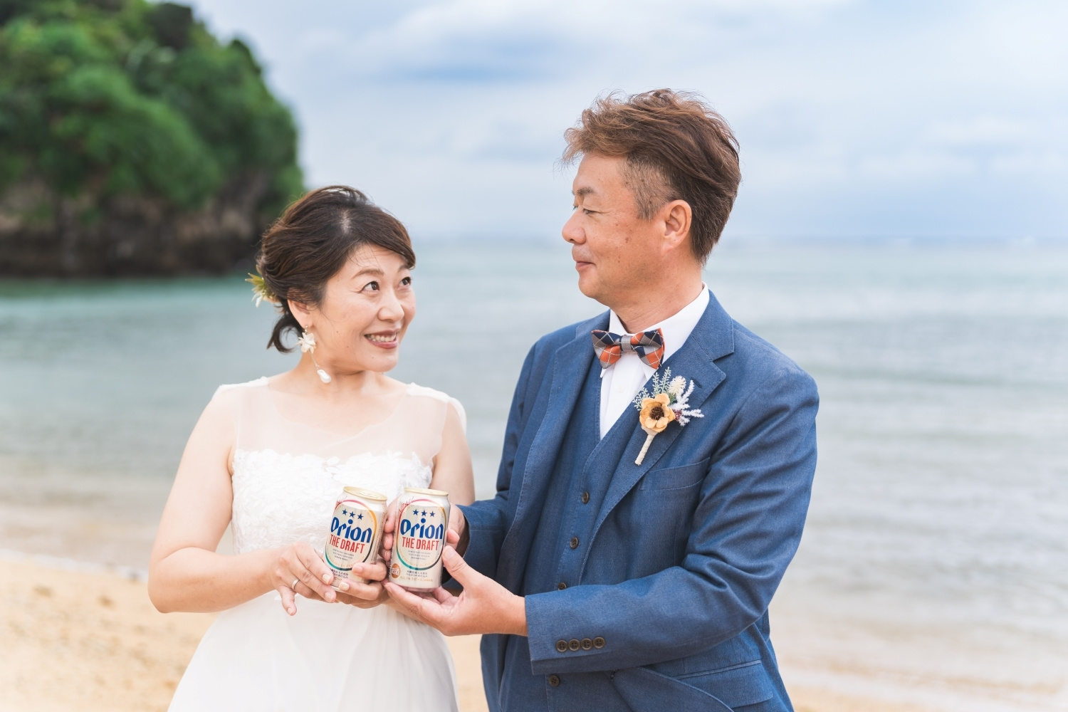 石垣島の海を背景にオリオンビールを持って見つめ合う新郎新婦