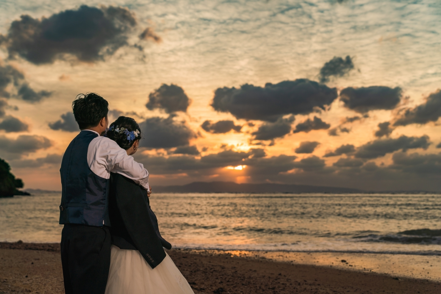 夕焼けに染まる海を眺める新郎新婦